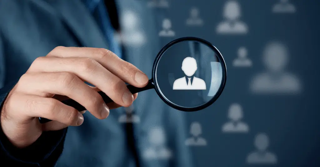 Image montrant une main tenant une loupe mettant en évidence une icône de profil sur un fond flou d’autres silhouettes, symbolisant l’hyper-personnalisation des campagnes marketing grâce à l’intelligence artificielle.